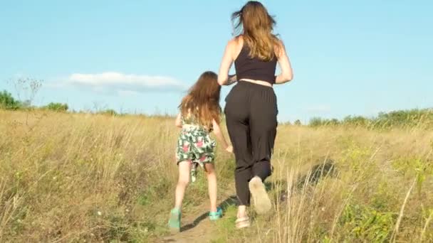 母と娘は夏の草の畑を走っています 幸せな母性と子供時代 — ストック動画