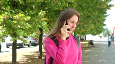 Sonbaharda şehrin sokaklarında dikilen bir kadın cep telefonuyla konuşuyor..