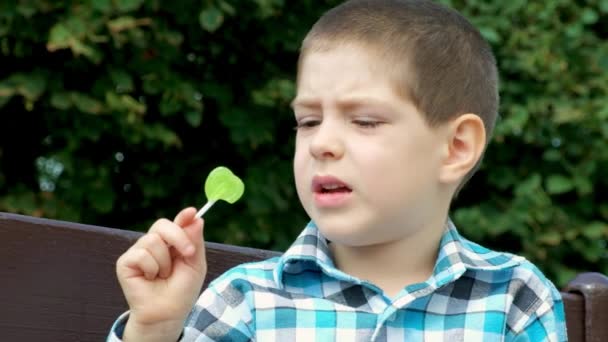 Egy Kisfiú Rágcsál Egy Nyalókát Kemény Cukorkák Ártalmasak Gyerekekre — Stock videók