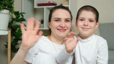 Genç bir anne ve altı yaşındaki oğlu kameraya bakarak el sallıyorlar. Anneler günün kutlu olsun.