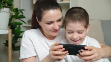 Anne ve oğlu akıllı telefondan oyun oynuyorlar. Eğlence eğlencesi, çocuk ve ebeveynlerin ortak ilgi alanları..