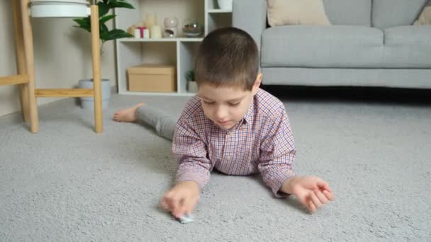 Little Boy Plays Toy Car Lying Floor Alone — Stock Video