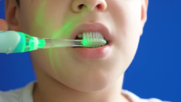 Małe Dziecko Myje Zęby Elektryczną Szczoteczką Zębów Podświetleniem Niebieskim Tle — Wideo stockowe