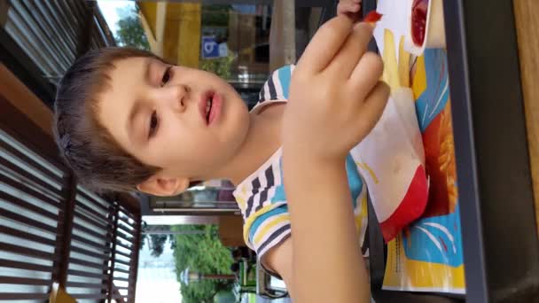 Мальчик Ест Картошку Фри Макдональдсе Сидя Открытым Столом — стоковое видео