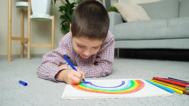 Mały Chłopiec Rysuje Tęczę Długopisami Szkicowniku Leżąc Dywanie Domu — Wideo stockowe