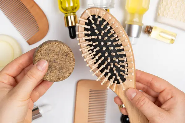 Solid shampoo and wooden comb in the hands of a woman. Eco Hair Care Products