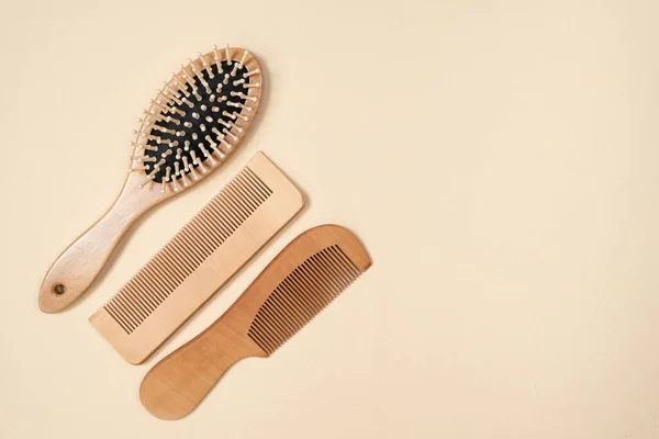 Wooden combs and hair care brush on beige background, top view, space for text