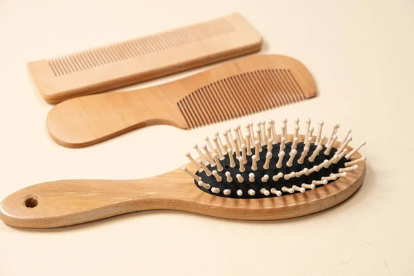 Wooden combs and hair care brush on beige background, top view.