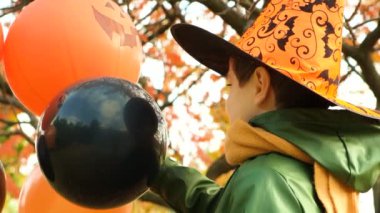 Mutlu Cadılar Bayramı çocuğu sonbaharda parkta balonlarıyla oynuyor.