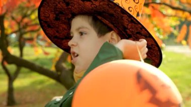 Mutlu Cadılar Bayramı çocuğu sonbaharda parkta balonlarıyla oynuyor.