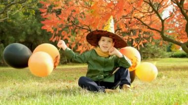 Mutlu Cadılar Bayramı çocuğu sonbaharda parkta balonlarıyla oynuyor.