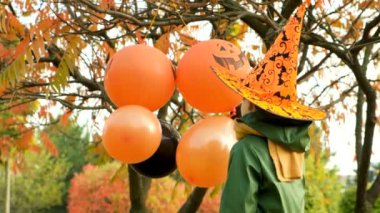 Mutlu Cadılar Bayramı çocuğu sonbaharda parkta balonlarıyla oynuyor.