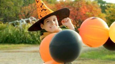 Mutlu Cadılar Bayramı çocuğu sonbaharda parkta balonlarıyla oynuyor.