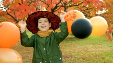 Mutlu Cadılar Bayramı çocuğu sonbaharda parkta balonlarıyla oynuyor.