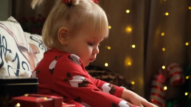 2岁的小女孩在圣诞节吃糖果 同时坐在家里享受各种礼物 — 图库视频影像