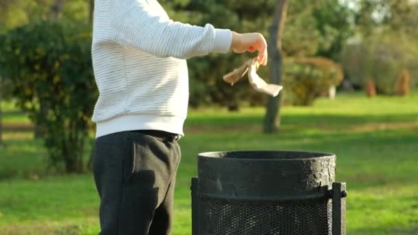 一个男孩把垃圾扔进公园的垃圾桶里 — 图库视频影像