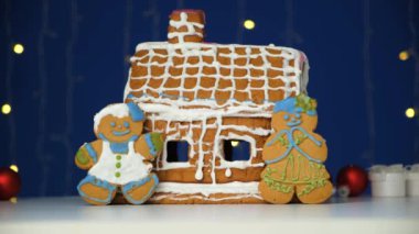 Erkek şeklinde Noel zencefilli ekmeği renkli şeker kreması ve kurabiye eviyle süslenir.