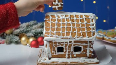 Bir zencefilli kek Noel evi yaratma ve dekore etme süreci. Bir kadın çatıya baca takıyor..