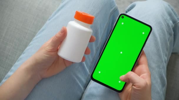 患者の手に緑色のスクリーン クロマ キーが付いているスマートフォンおよび薬の瓶 — ストック動画