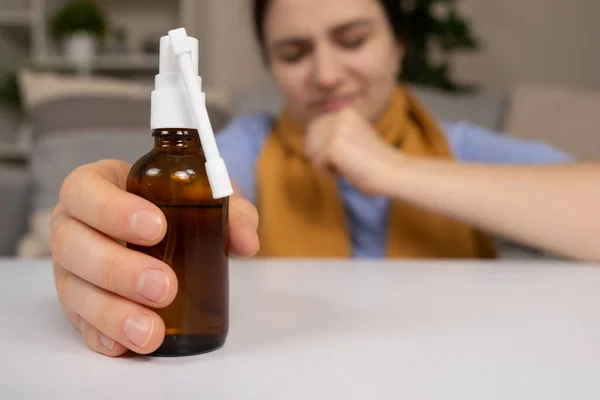 A bottle of medicine to treat a sore throat and cough in a patients hand