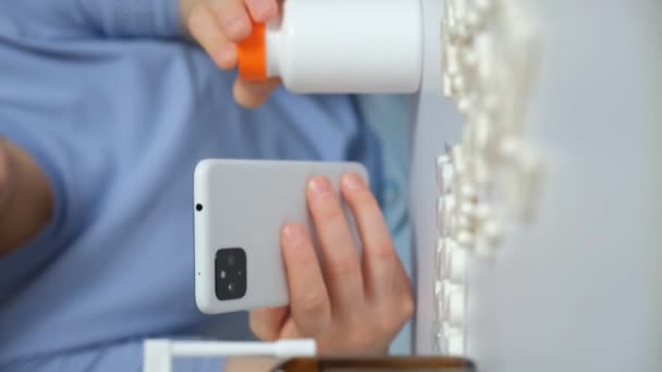 自宅でスマートフォンを使用してインターネットで薬の使用のための指示を読んでいる女性 — ストック動画