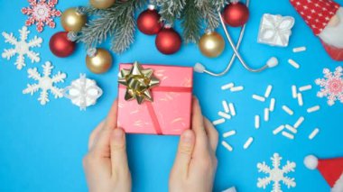 İlaç ve kış tatilleri Noel ve yeni yıl - bir doktorun elleri ve hediye üst görünümü.