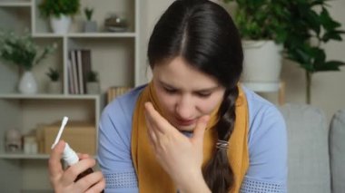 Boğazı ağrıyan bir kadın boğazına sprey sıkar..