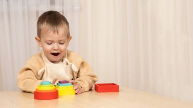 İki yaşındaki bir çocuk, mantık ve motor becerilerini geliştirmek için tahta oyuncaklarla oynar..