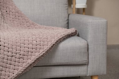 Kanepenin üzerinde toz pembe açık grimsi kırmızı bir battaniye örüyordu.