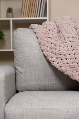 Kanepenin üzerinde toz pembe açık grimsi kırmızı bir battaniye örüyordu.