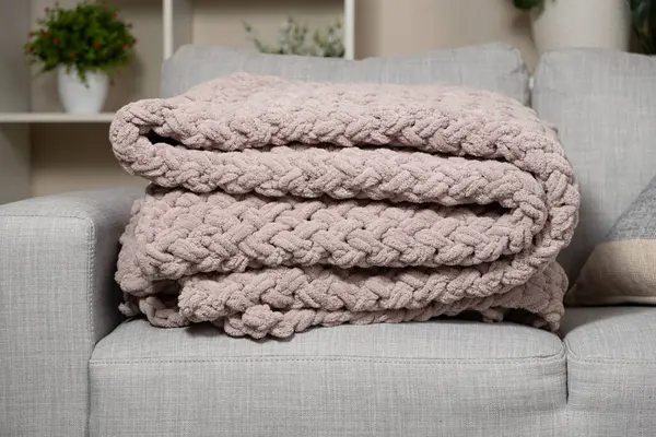 Kanepenin üzerinde toz pembe açık grimsi kırmızı bir battaniye örüyordu.