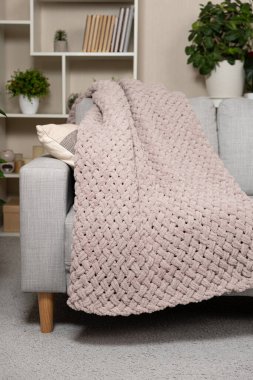 Kanepenin üzerinde toz pembe açık grimsi kırmızı bir battaniye örüyordu.