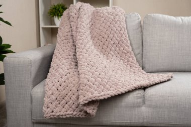 Kanepenin üzerinde toz pembe açık grimsi kırmızı bir battaniye örüyordu.