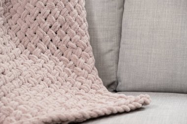 Kanepenin üzerinde toz pembe açık grimsi kırmızı bir battaniye örüyordu.