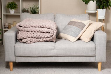 Kanepenin üzerinde toz pembe açık grimsi kırmızı bir battaniye örüyordu.