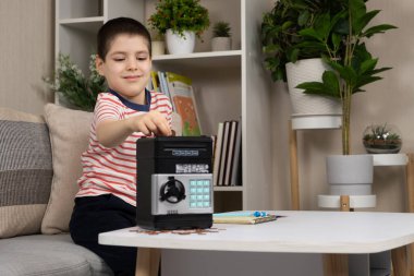 Küçük bir çocuk kumbaraya para koyuyor. Çocuklar için finansal okur yazarlık