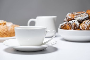 Kahvaltı çatal bıçakları. Boş bir kahve fincanı, bir sürahi süt ve bir tabak kruvasan ve çörek..