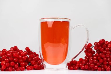 Cam fincanda sıcak viburnum çayı, beyaz arka planda çift tabanlı.