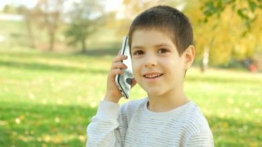 Küçük çocuk parkta yürürken telefonda konuşuyor..