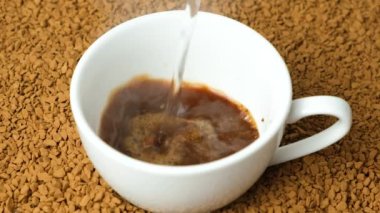 Hazır kahve yapmak, granüllerin üzerine kaynar su dökmek. Lezzetli aromalı granüllü kahve, yavaş çekim.