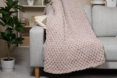 Kanepenin üzerinde toz pembe açık grimsi kırmızı bir battaniye örüyordu.