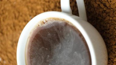 Kahve fincanının arka planında sıcak hazır kahve, içkinin yüzeyinde kabarcıklar, buhar geliyor.