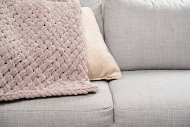 Kanepenin üzerinde toz pembe açık grimsi kırmızı bir battaniye örüyordu.