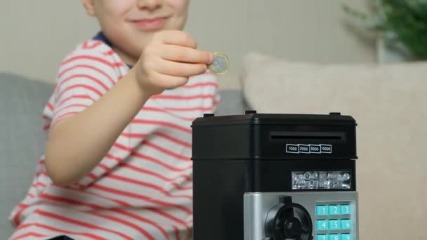 一个小男孩把一枚硬币放在一个安全的储蓄罐里 儿童金融知识普及 — 图库视频影像