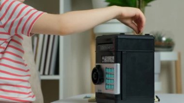 Okullu bir çocuk kumbaraya bozuk para koyuyor. Çocuklar için finansal okur yazarlık