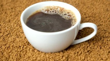 Kahve fincanının arka planında sıcak hazır kahve, içkinin yüzeyinde kabarcıklar, buhar geliyor.