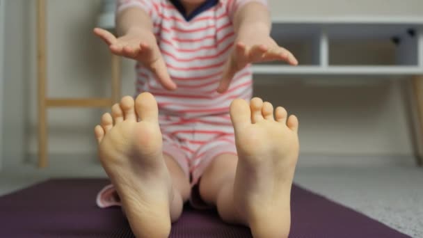 Ребенок Делает Упражнения Растяжку Дома Пытаясь Дотянуться Пальцев Ног Руками — стоковое видео