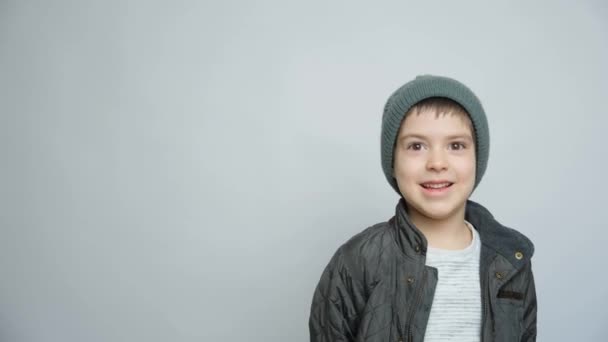 白い背景で笑う帽子 ジャケット ミトンで幸せな子供の肖像画 — ストック動画