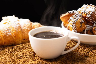 Bir fincan hazır kahve taneleri ve çörekler. Güzel ve lezzetli kahvaltı.