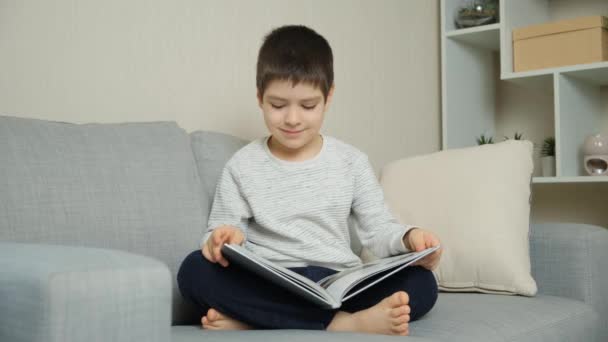 かわいい 歳の子供は本を飛び回り 写真を見て 読むことを学びます — ストック動画